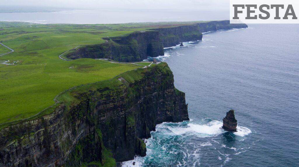 Stunning aerial view of the Cliffs of Moher, County Clare, Ireland with lush green landscapes and ocean waves.
